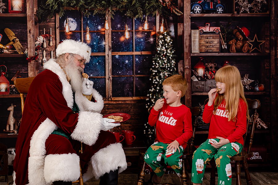 siblings eating cookies with santa